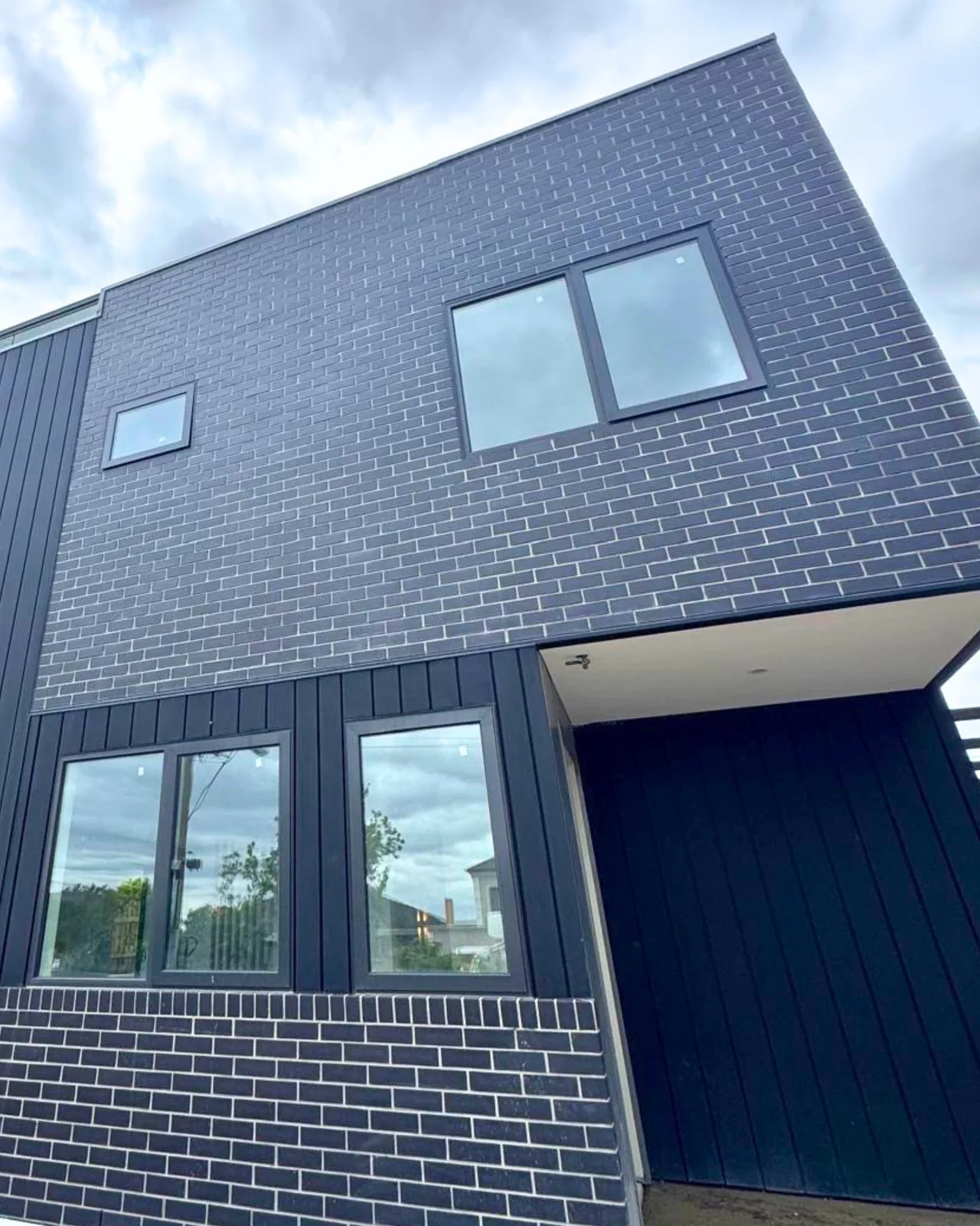 Black brick and rail facade to the upper level of a Balwyn townhouse